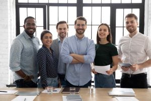 Une équipe unie de six personnes se tient avec confiance et sourires, démontrant un parfait alignement d'équipe. Au premier plan, le leader se dresse fièrement, incarnant la vision et la direction commune. Derrière lui, les membres de l'équipe, manifestement satisfaits et motivés, reflètent l'harmonie et la réussite collective. Leur posture et leurs expressions trahissent une synergie réussie et une célébration des objectifs atteints, illustrant visuellement l'essence de l'alignement d'équipe.