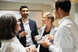 Une équipe de cinq dirigeants ayant participé à une formation en leadership dans le cadre du programme de coaching en leadership qui discute en prenant un café